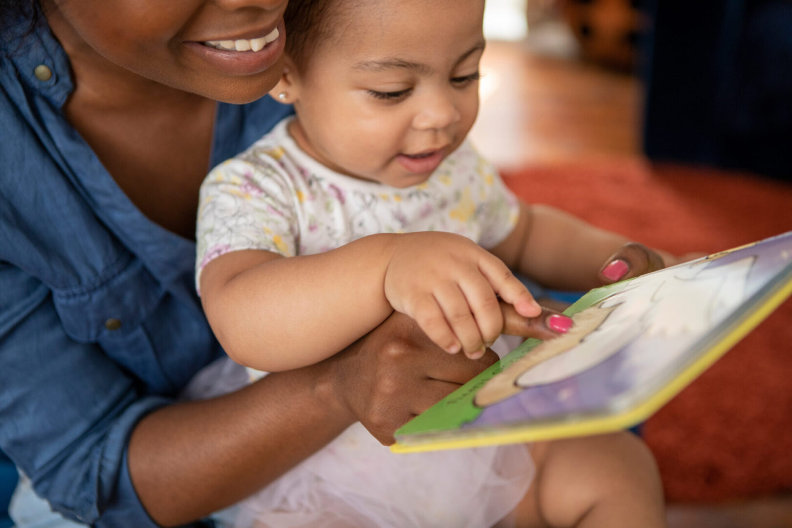 Mother reading to baby daughter (12-17 months) at home